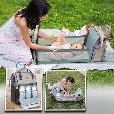 Sac à langer gris, spacieux, montrant un bébé allongé paisiblement dedans alors que sa mère peut changer sa couche à l'abri des regards.