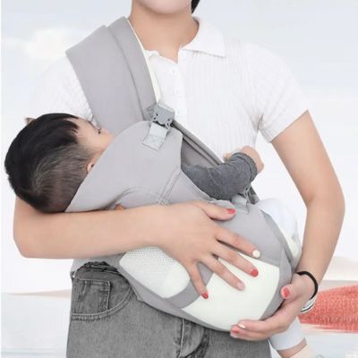 Enfant couché dans son porte bébé gris porté par sa mère.