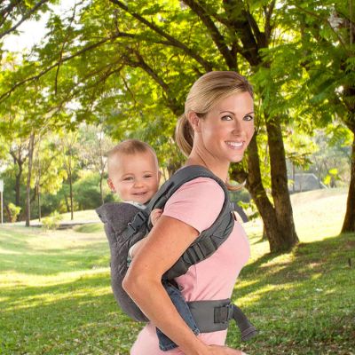 Maman qui porte son bébé dans un porte bébé de manière dorsal.