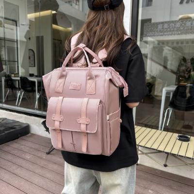 Démonstration d'un sac à dos à langer rose comme sac à dos léger avec plusieurs compartiments.