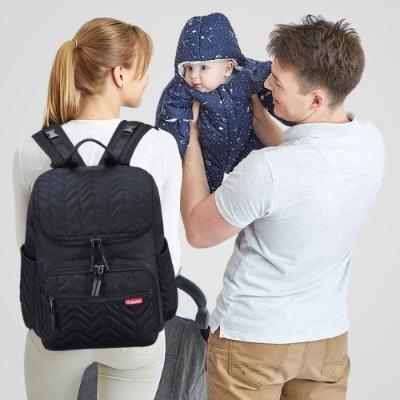 Sac à langer bébé présenté en sac à dos avec maman et papa qui tient son bébé dans ses bras.