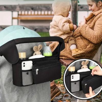 Sac a langer montrant une maman et son bébé à l'extérieur assis sur un banc et le sac dans lequel vous pouvez y mettre plein de trucs à l'intérieur de ses pochettes.