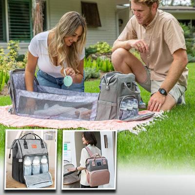 Sac à langer avec les parents regardant leur bébé couché confortablement dedans et démontrant que ce sac peut se convertir en sac à dos facilement transportable.